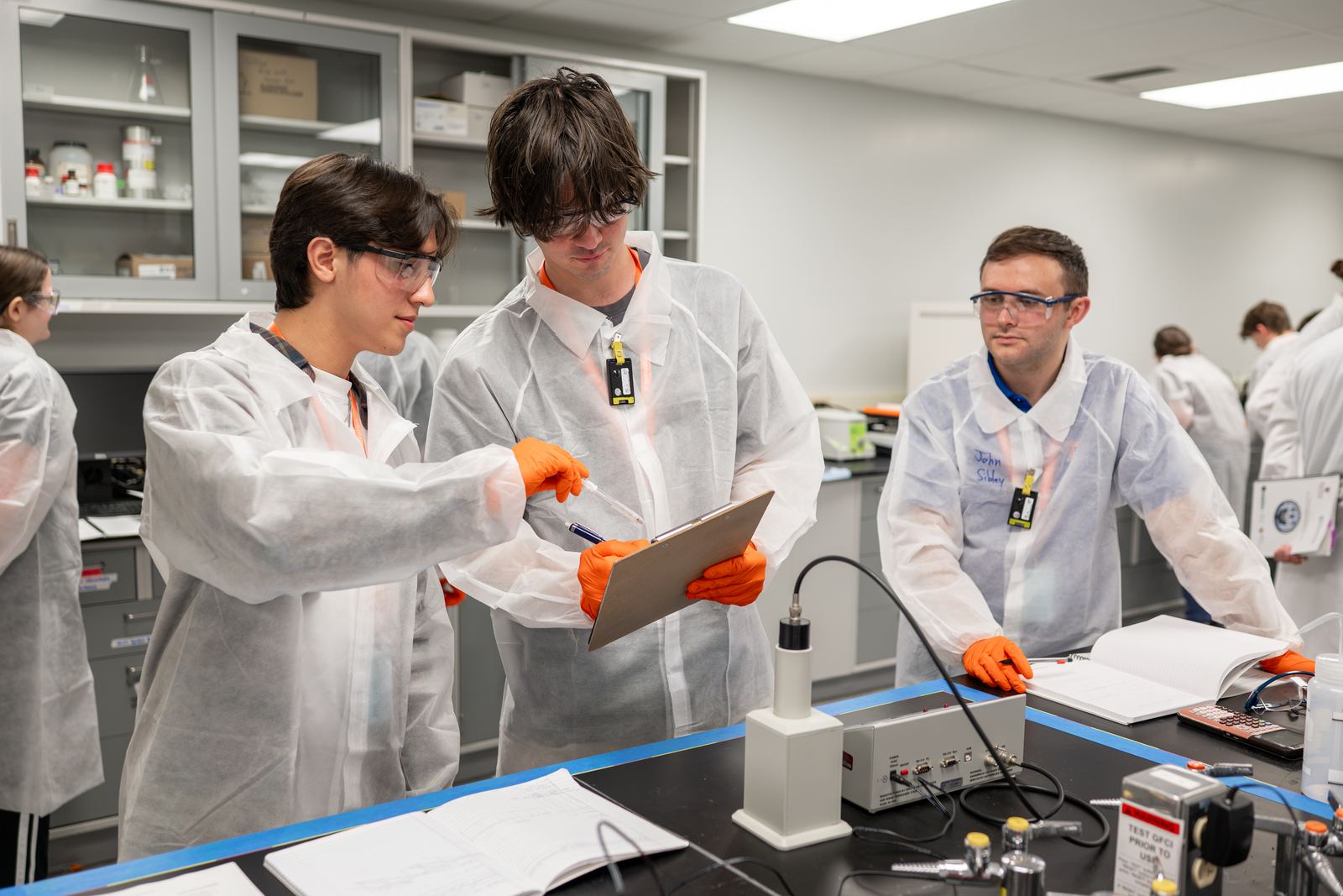 NCSS students compare notes beside a detector during a lab exercise